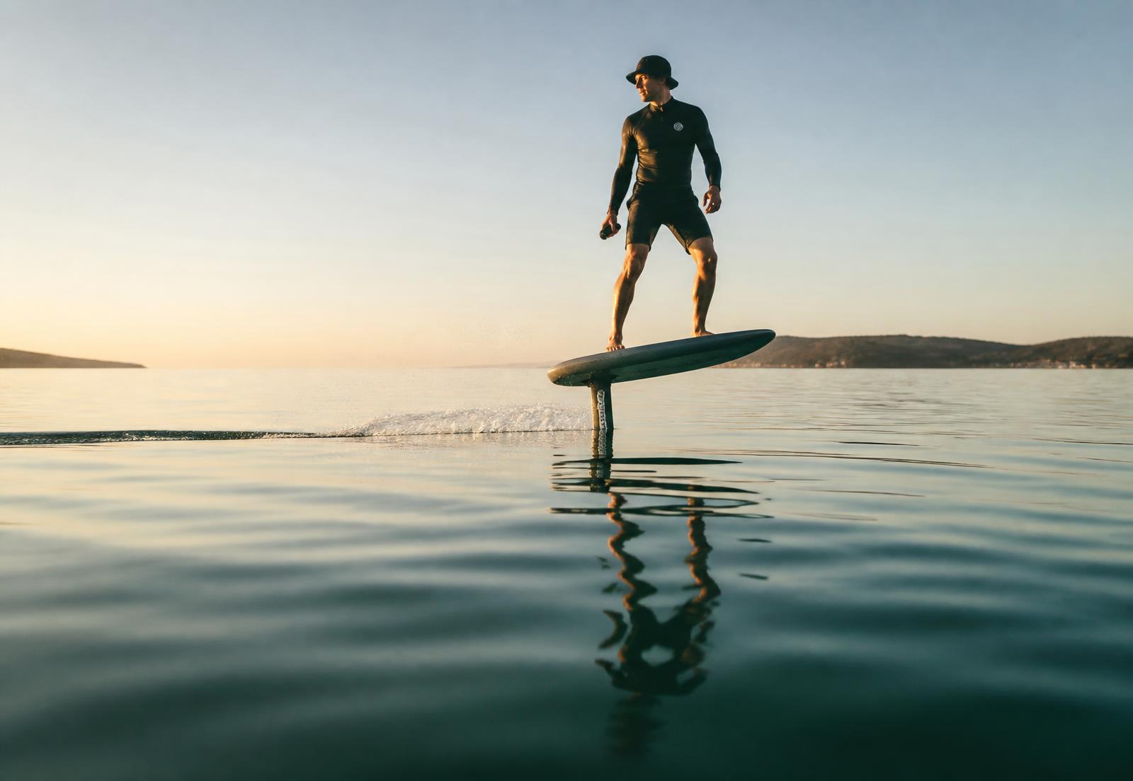 A rider flying an electric hydrofoil board above flat water